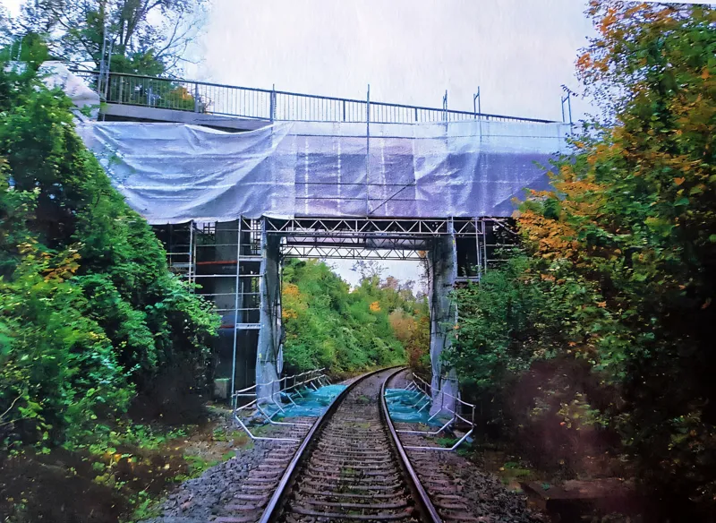 Bahnbrücke mit Gerüst und Schutzplane über dem Gleis