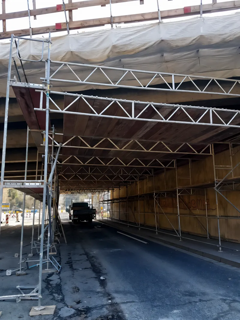 Straßenunterführung, Gerüst mit Schutzdach über der Fahrbahn, LKW fährt darunter durch