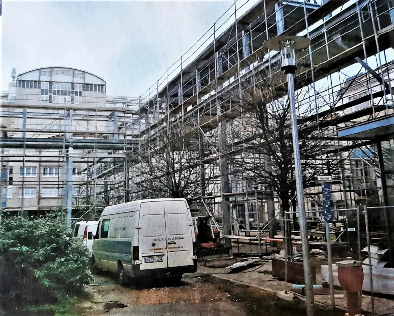 Industriegebäude mit Gerüst über die gesamte Fassade, Baustellenzufahrt im Vordergrund