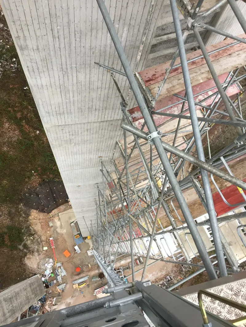 Blick vom Pfeilergerüst senkrecht nach unten auf Beläge, Diagonalen und die Baustelle am Boden