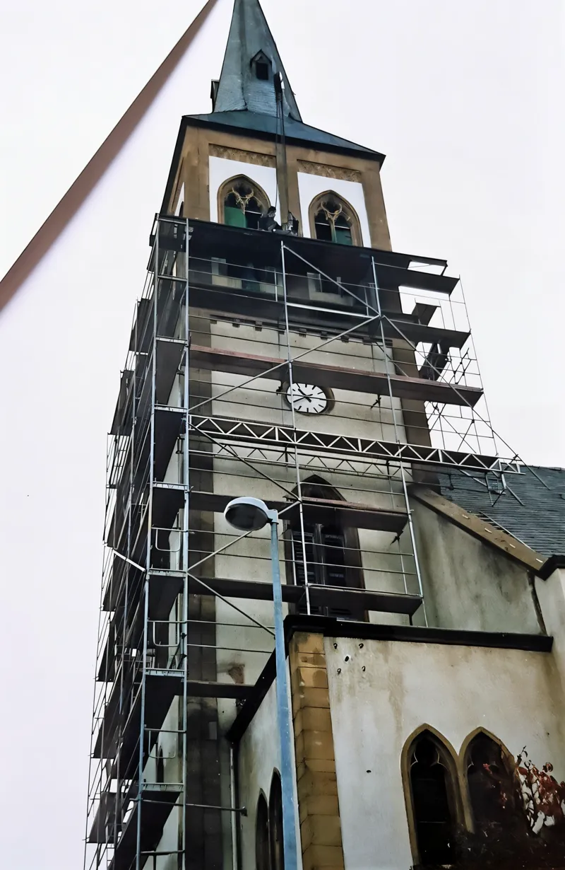 Kirchturm mit Uhr, eingerüstet bis unter die Glockenstube