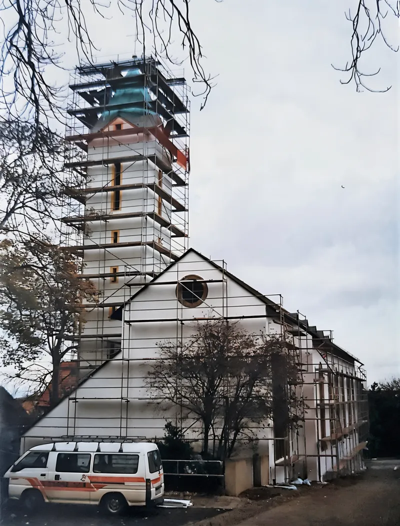 Kirche mit Turm und Langhaus, beide Bauteile eingerüstet, Blick von der Straße